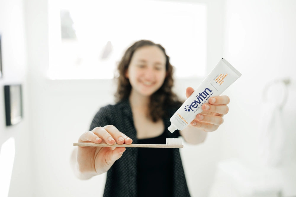 Woman squeezing revitin's toothpaste onto a toothbrush